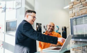 Zwei Personen stehen in einem modernen Büro und besprechen Inhalte auf einem Laptop.