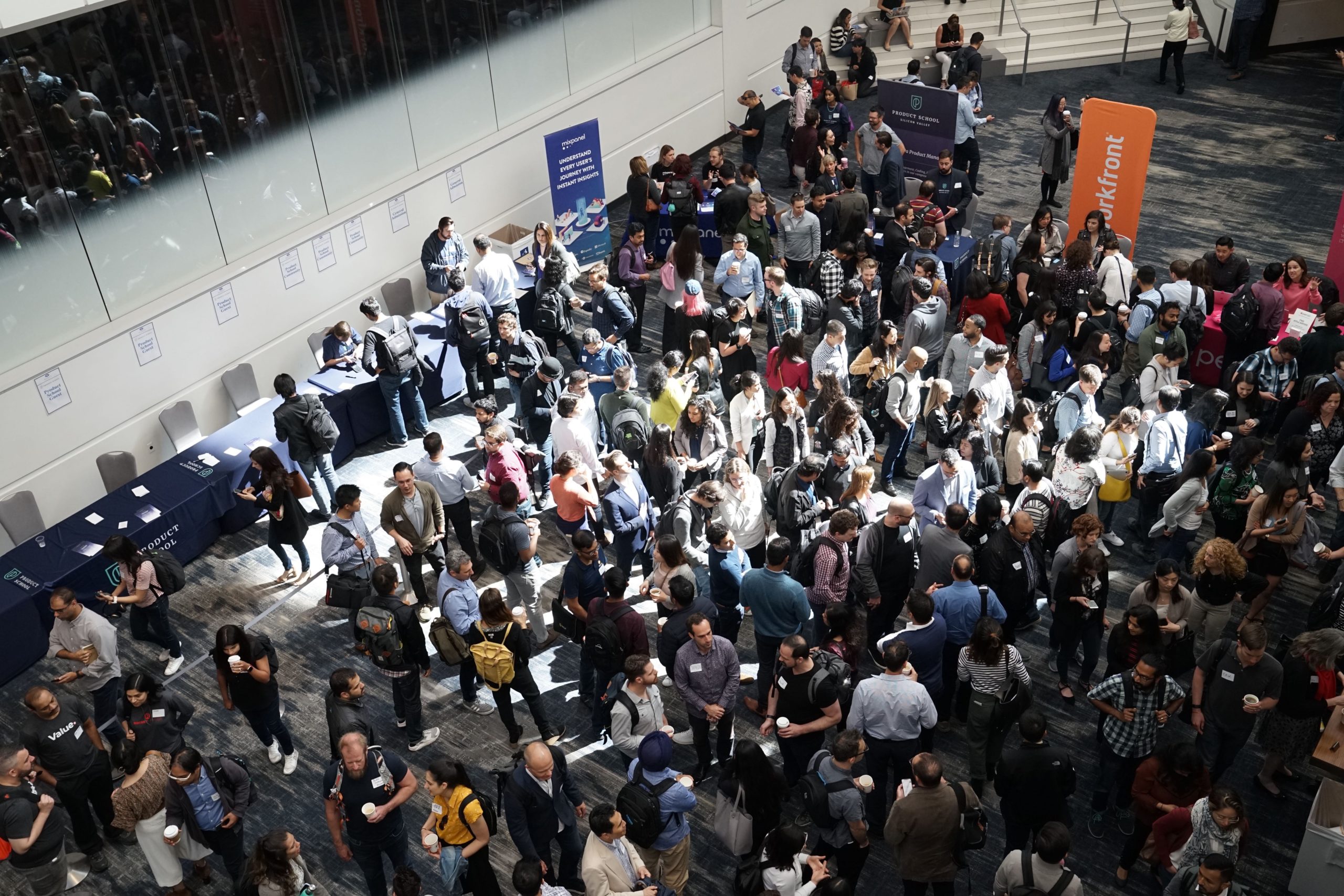 Zahlreiche Personen besuchen eine Konferenz oder Messe, tauschen sich an Ständen aus und vernetzen sich.