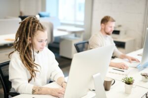 Zwei Personen arbeiten konzentriert an ihren Computern in einem hellen, modernen Büro.